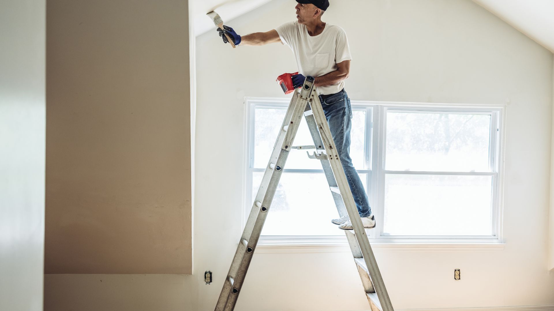 man on a ladder fixing a ceiling